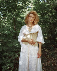 Full length of woman standing by tree in forest