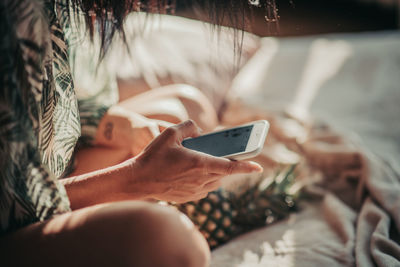 Midsection of man using mobile phone on bed