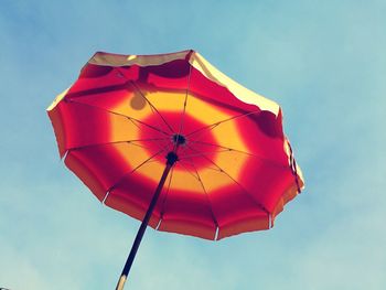 Low angle view of red umbrella against blue sky