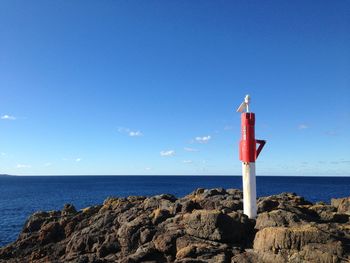 Lighthouse by sea against blue sky