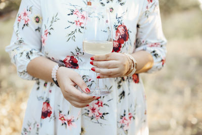 Midsection of woman holding wineglass outdoors
