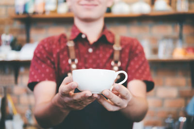 Midsection of woman holding coffee cup at cafe