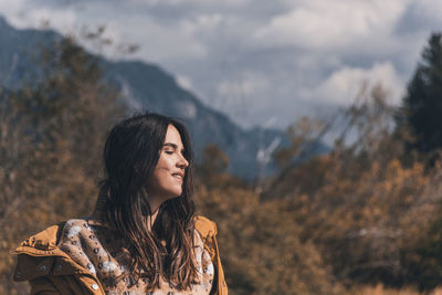 Beautiful young woman wearing autumn clothes, enjoying sunlight in mountains