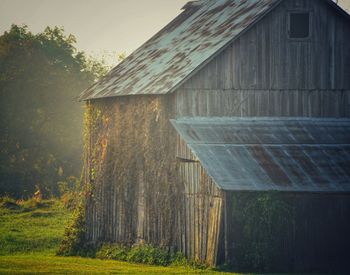 Barn on field by building against sky