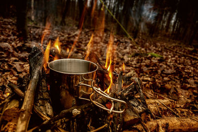 Water in metallic container on campfire at forest