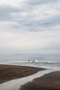 Scenic view of beach against cloudy sky