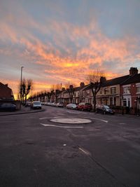 Road in city against sky at sunset