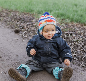 High angle view of happy girl sitting on dirt road during winter