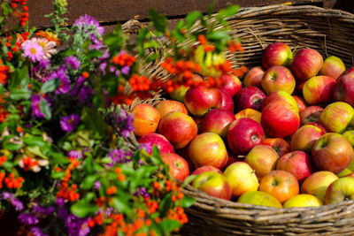 High angle view of fresh apples in wicker basket by flowers