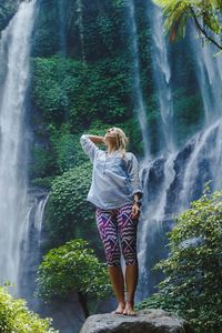 Woman standing by waterfall