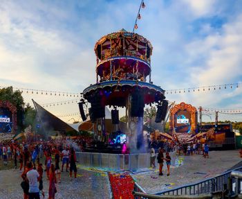 People in amusement park against sky in city