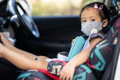 Cute little girl wearing healthy face mask prevent virus and pm2.5 in carseat