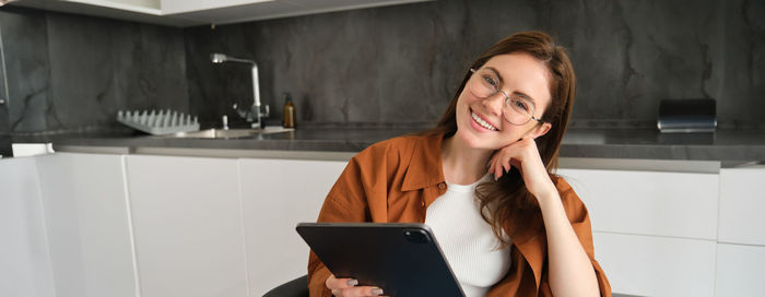 Young woman using mobile phone while standing in office