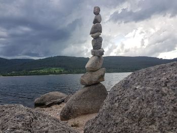Stack of stones on rock against sky