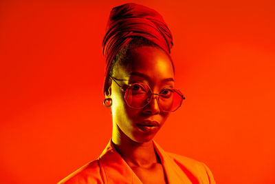 Portrait of young man wearing eyeglasses against red background