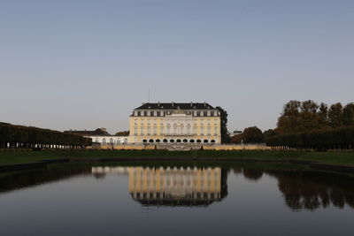 Reflection of building in lake against clear sky