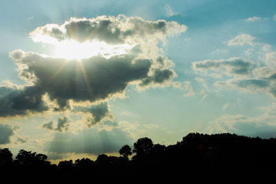 Low angle view of sunlight streaming through clouds