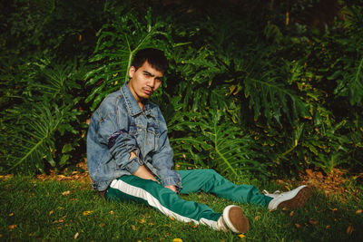 Portrait of young man sitting on field at park