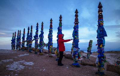 Full length of person touching pole tied up with fabrics at beach during winter