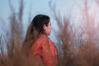 Side view of woman looking away against sky