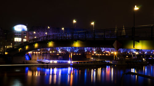 Illuminated bridge over river at night