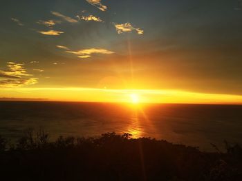 Scenic view of sea against dramatic sky during sunset