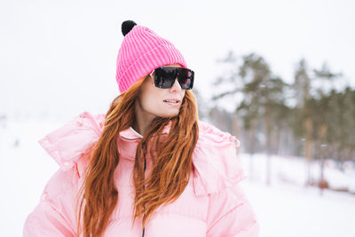 Portrait of young woman wearing warm clothing standing on snow
