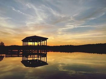 Gazebo in lake against sky during sunset