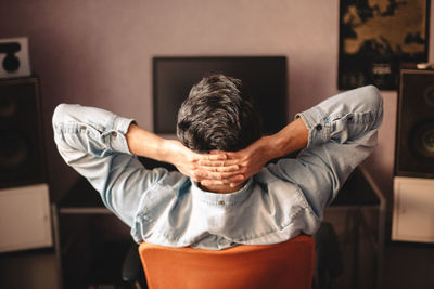 Rear view of man sitting on chair at home