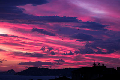 Silhouette buildings against dramatic sky during sunset