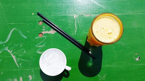 High angle view of orange juice on green table on sunny day