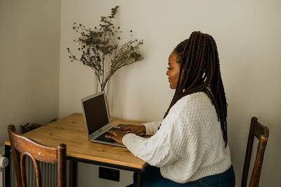 Rear view of woman using laptop at home