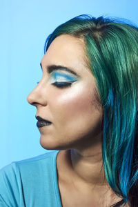 Close-up portrait of young woman against blue background