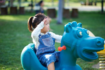 Girl sitting on blue spring ride at park