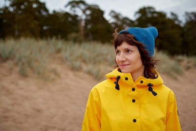 One with nature. mature beautiful woman looking to forest in bright yellow jacket 