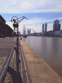 Bridge over river by city buildings against sky