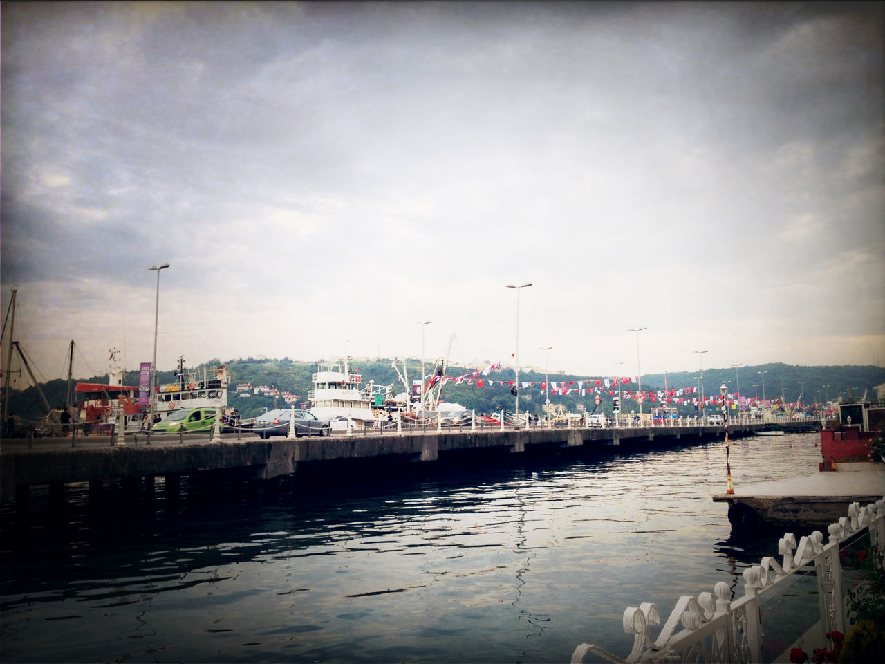 sky, water, bird, building exterior, nautical vessel, built structure, architecture, transportation, harbor, cloud - sky, flying, mode of transport, animal themes, moored, waterfront, cloudy, wildlife, boat, cloud, animals in the wild