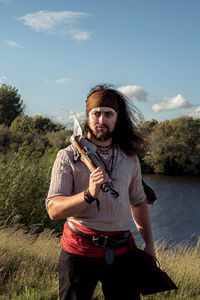 Portrait of man standing on field against sky