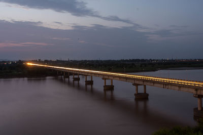 Bridge over river against sky at night