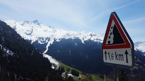 Sign board on mountains against sky