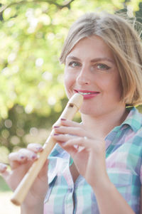 Young beautiful caucasian girl dressed in pinup style plays the flute and smiles