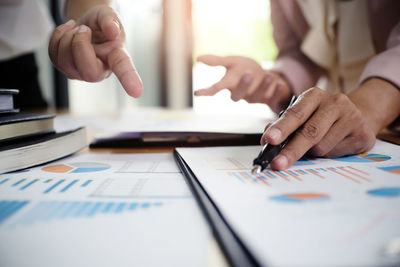 Cropped image of businesspeople working over graph in office