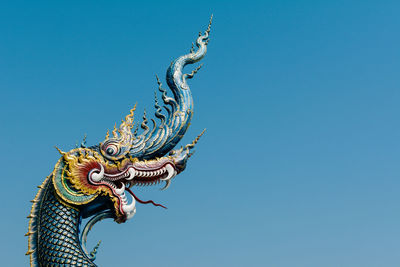 Low angle view of dragon statue at wat rong khun against clear sky