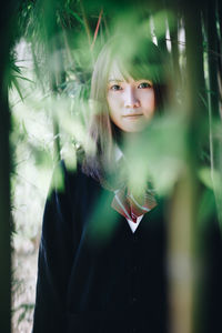 Portrait of woman standing against tree