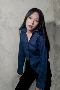 Portrait of woman standing against wall