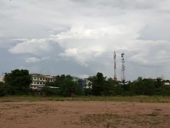 Traditional windmill on field by building against sky