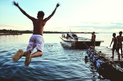 Shirtless man diving into sea against sky