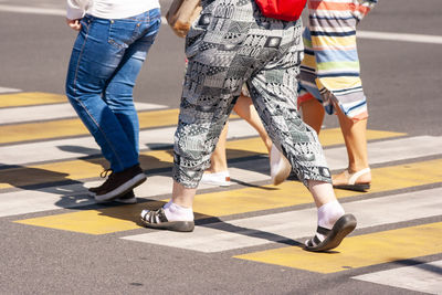 Low section of women walking on zebra crossing