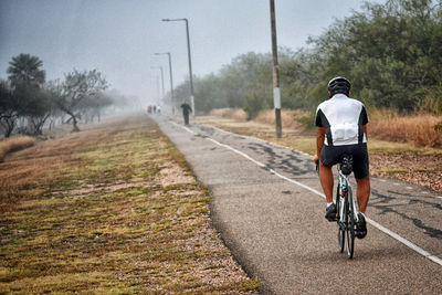 Rear view of man riding bicycle on road