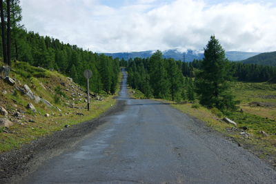 Road amidst trees in forest against sky